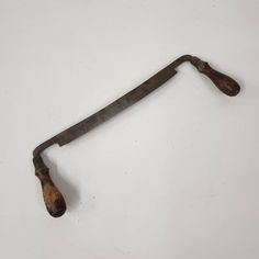 an old metal handle with wooden handles on a white surface and no one around it