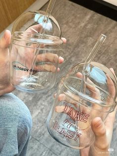 two people holding empty glass jars with the words happy day written on them, and one person's hands holding a straw