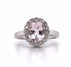 an oval shaped pink diamond surrounded by white diamonds in a halo setting on a silver band