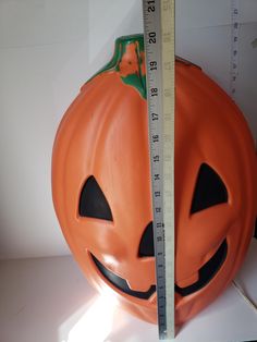 an orange pumpkin with a measuring tape around it's neck and eyes on display