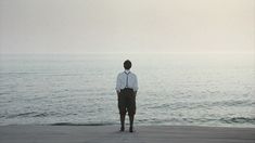 a man standing on top of a beach next to the ocean