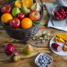 an assortment of fruits and snacks on a wooden table next to a bowl of fruit