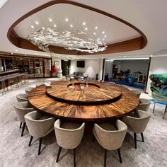 a large wooden table surrounded by chairs in a room with high ceiling lights and chandelier