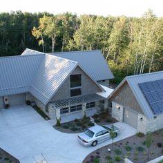 an aerial view of a house with solar panels on the roof and car parked in front