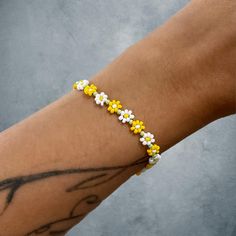 White, yellow, and green flower bracelet with silver lobster clasp. Adjustable Flower Bracelets With Lobster Clasp, Yellow Flower-shaped Jewelry For Spring, Casual Flower-shaped Jewelry For Spring, Spring Yellow Flower-shaped Jewelry, Casual Flower-shaped Spring Jewelry, Casual Spring Flower Jewelry, White Spring Jewelry For Friendship, Yellow Flower-shaped Jewelry With Flower Decoration, Elegant Yellow Flower-shaped Jewelry With Flower Decoration