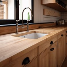 a kitchen with wooden counter tops and black knobs on the faucet above the sink