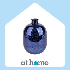 a blue glass vase sitting on top of a white house with the words at home above it