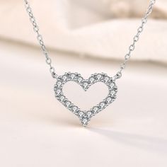 This exquisite piece embodies a perfect blend of elegance and sophistication. Crafted with utmost precision, the heart-shaped pendant is made from sterling silver, radiating a timeless charm. The round cut stones glisten with a captivating brilliance, adding a touch of enchantment to your every ensemble. Wear this mesmerizing necklace as a symbol of love and purity, embracing its graceful beauty close to your heart.Weight: 2.2 gWidth: 15 mmHeight: 13 mmMaterial: 925 SilverPlating Color: SilverLe