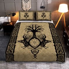 a bed covered in a black and gold comforter with an intricate tree on it