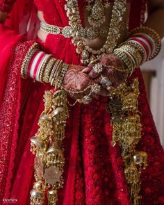 a woman in red and gold outfit with jewelry on her hands