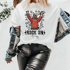 Rock On T-Shirt, Rocker shirt, Rodeo fan gear, Rodeo Kids, Brahman Darlin, NFR Fashion, NFR Afterparty, NFR number on back shirt, Buckle Bunny tee Thank you for shopping my small business. Please message me if you have questions. This is a physical shirt that is made when you order it and shipped out to you. If you love the design and would like it on a different type of item, rather message me and I will do what I can to get a different product to you. Shipping times are 2-5 days, but the longe Trendy Music Festival Fan Merchandise Tops, Trendy Fan Merchandise Tops For Music Festivals, Trendy Tops For Music Festivals Fan Merchandise, Rock Style Crew Neck T-shirt With Screen Print, Short Sleeve T-shirt For Music Festival In Fall, Trendy T-shirt For Music Festival In Fall, Trendy Fall Music Festival T-shirt, Trendy Fall T-shirt For Music Festival, Trendy Crew Neck Shirt For Concert