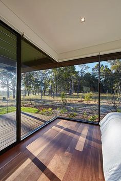 a bedroom with wooden floors and sliding glass doors that look out onto the woods outside