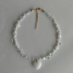 a white beaded bracelet with a heart charm