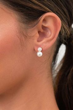 a woman wearing a pair of earrings with pearls on the end of her ear,