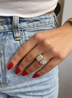 a woman's hand with red nails and a ring on her left wrist, wearing jeans