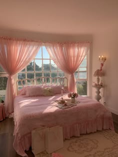 a bedroom with pink bedding and curtains on the window sill, next to a large rug