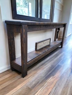 a wooden table sitting on top of a hard wood floor next to a wall mounted mirror