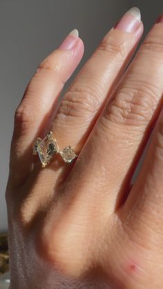 a woman's hand holding an engagement ring with two diamonds on the middle of it