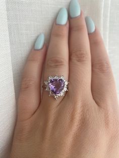 a woman's hand wearing a ring with an amethorate and diamonds