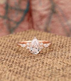 an engagement ring with three pear shaped diamonds in the center on top of a burlock