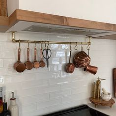 pots and pans are hanging on the wall above the stove top in this kitchen