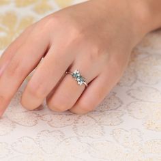 a woman's hand wearing a ring with three stones on the middle of it