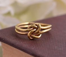 two gold rings sitting on top of a brown book next to white flowers in the background