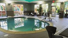 an indoor swimming pool surrounded by chairs and tables