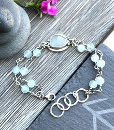 "light blue aquamarine encased in sterling silver bracelet. Dimensions: length 19cm/7,5\", best fits a 6,5\" - 7,5\" wrist;   The bracelet is slightly adjustable with hammered circles, oxidized and polished to enhance the detail of the metalwork. The bracelet is handcrafted with care in my studio. Purchases are nicely packaged, ready for gift giving or a special treat for yourself.  Matching ring is available in my shop: https://www.etsy.com/listing/1519668690/sterling-silver-ring-with-faceted?c Adjustable Aquamarine Bracelets With Natural Stones, Adjustable Silver Aquamarine Bracelets, Aquamarine Bracelet Jewelry As A Gift, Adjustable Silver Aquamarine Bracelet, Aquamarine Bracelet Jewelry Gift, Adjustable Aquamarine Silver Bracelet, Double Strand Sterling Silver Bracelet For Gift, Sterling Silver Double Strand Bracelet Gift, Handmade Adjustable Aquamarine Bracelet