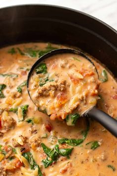 a ladle scooping out some soup from a pot filled with it and ready to be eaten