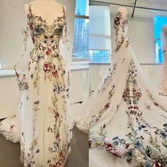 two dresses on display in front of a window and one is white with red flowers