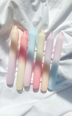 four different colored candles sitting on top of a white sheet