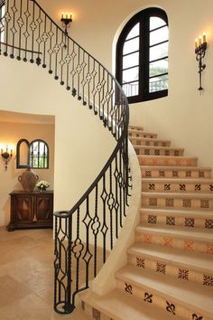 a staircase leading up to the second floor with arched windows and wrought iron railings