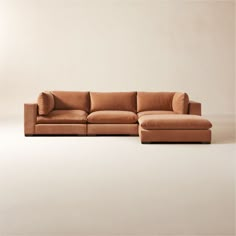 a brown couch sitting on top of a white floor next to a chair and ottoman