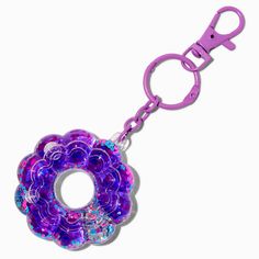 a purple keychain with a flower design on the front and back ends, hanging from a metal hook