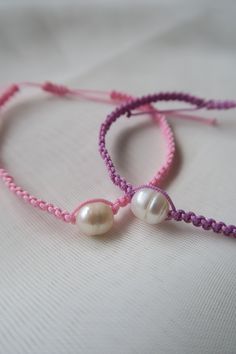 two pink and purple bracelets with white pearls on the end of each bead