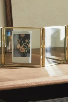 two gold frames with flowers in them on a table