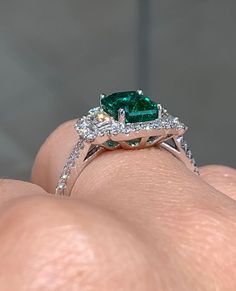 Emerald statement cocktail ring is a great way to create an elegant, princess-like look. The center stone is emerald cut shape and has gorgeous facets. For extra sparkle, 2 Emerald cut side 0.30ctw diamonds and has been framed by 48 round brilliant cut 0.37ctw diamonds forming a beautiful halo around. Metal: 18K white goldDiamond Weight : (48) 0.37ctw Side Diamonds: (2) 0.30ctwEmerald Weight: 1.64ctWidth: 13mm X 15mm Emerald: W 8 mm X L 5.7mm Estimated production time is 4 - 5 weeks Luxury Green Emerald Halo Ring, Emerald Cut Fine Jewelry Ring For Party, Fine Jewelry Emerald Cut Rings For Party, Party Rings With Prong Setting And Emerald Cut, Emerald Cut Rings With Prong Setting For Party, Exquisite Emerald Cut Emerald Ring With Accent Stones, Exquisite Emerald Cut Ring With Accent Stones, Gia Certified Elegant Square Cut Diamond Ring, Emerald Cut Center Stone Jewelry For Party