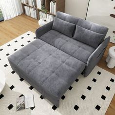 a grey couch sitting on top of a white rug