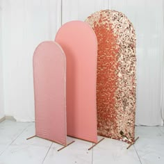 three pink and gold sequins are standing next to each other in front of a white wall