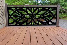 a wooden deck with metal railing and trees in the background