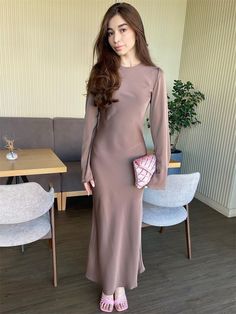 a woman standing in front of a table wearing a brown dress and pink shoes with her hand on her hip