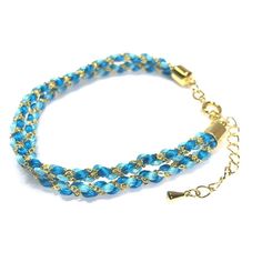 a bracelet with blue beads and gold clasps on a white background, the chain has an arrow charm attached to it