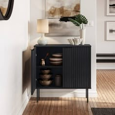 a black cabinet with plates and bowls on it next to a wall mounted art piece