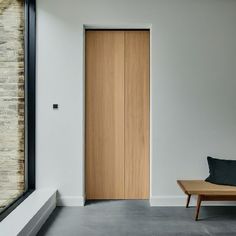 an empty room with a wooden door in the center and a bench next to it