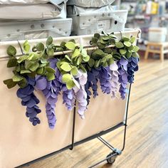 purple and green flowers are hanging from a rack