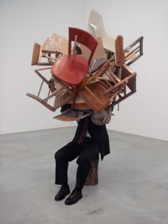 a man sitting on top of a tree stump with lots of chairs in his back