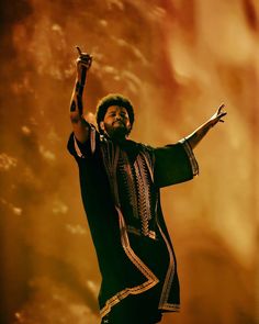 a man with his arms up in the air while holding a microphone and singing on stage