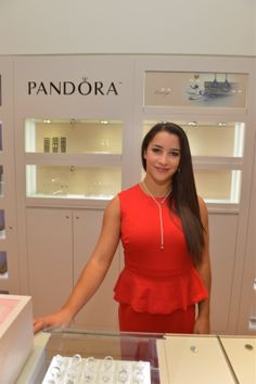 a woman in a red dress standing next to a display case with jewelry on it