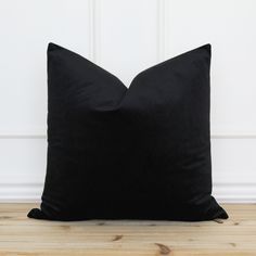 a black pillow sitting on top of a wooden floor